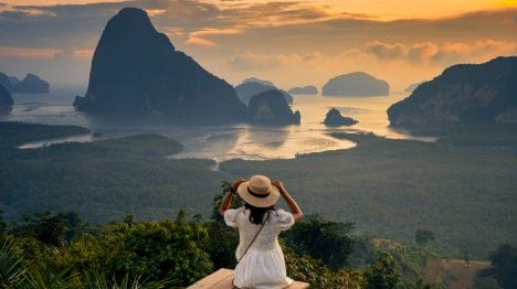MY-THAILAND-Woman-at-the-top-of-a-mountain-overlooking-Phang-Nga-Bay-at-sunset