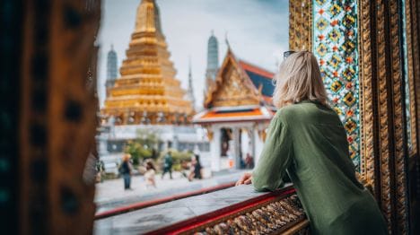 MY-THAILAND-Woman-leaning-on-an-open-window-looking-at-the-grand-palace-in-thailand